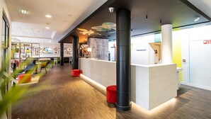 A modern lobby with a reception desk, wooden flooring, and colorful seating areas. - Holiday Inn Express Hasselt by IHG (Hasselt)