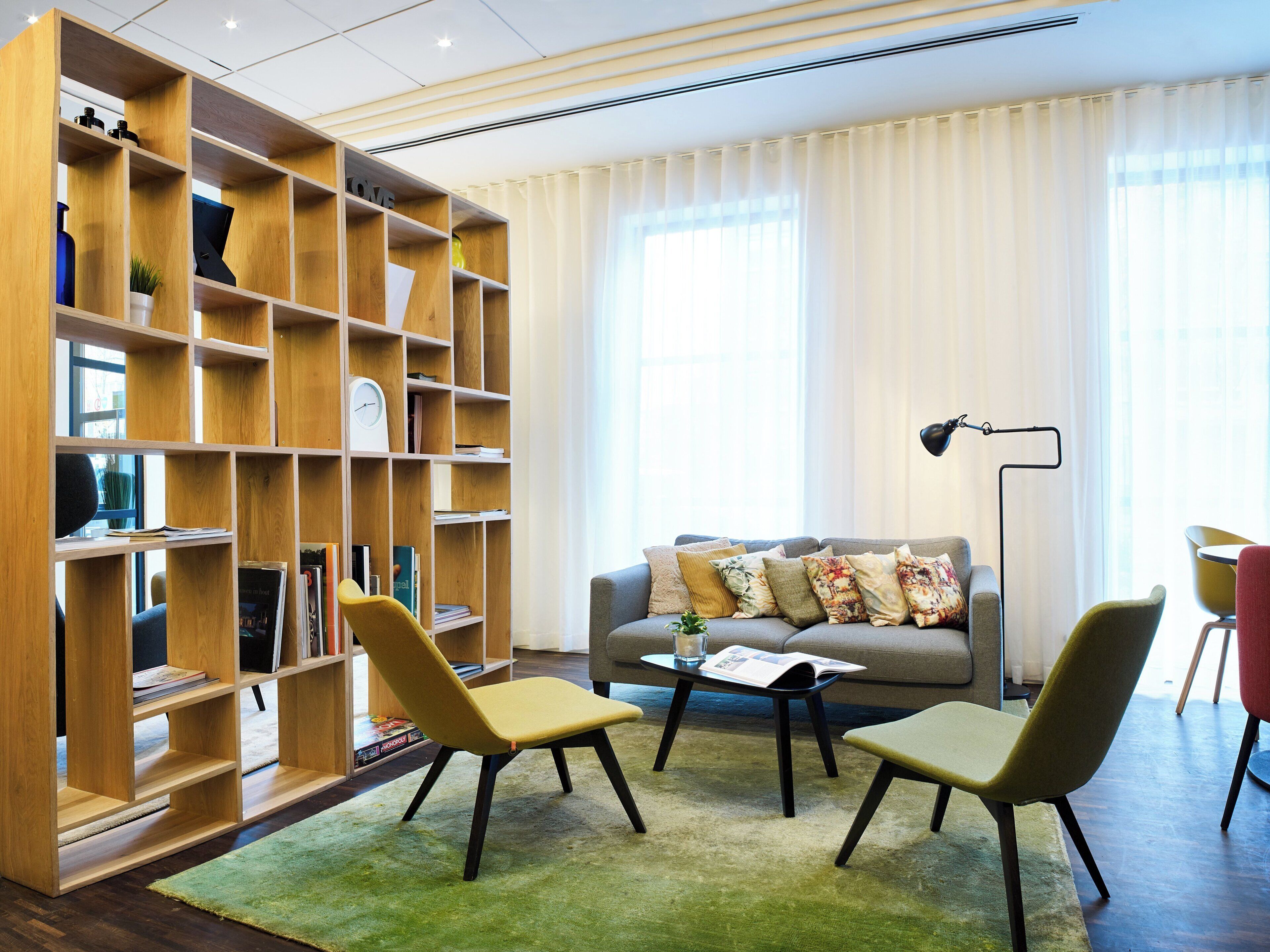 Una sala moderna con una estantería, un sofá y dos sillones.