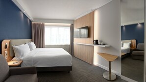 A modern hotel room with a large bed, a TV mounted on the wall, a small table, and a seating area. - Holiday Inn Express Hasselt by IHG (Hasselt)