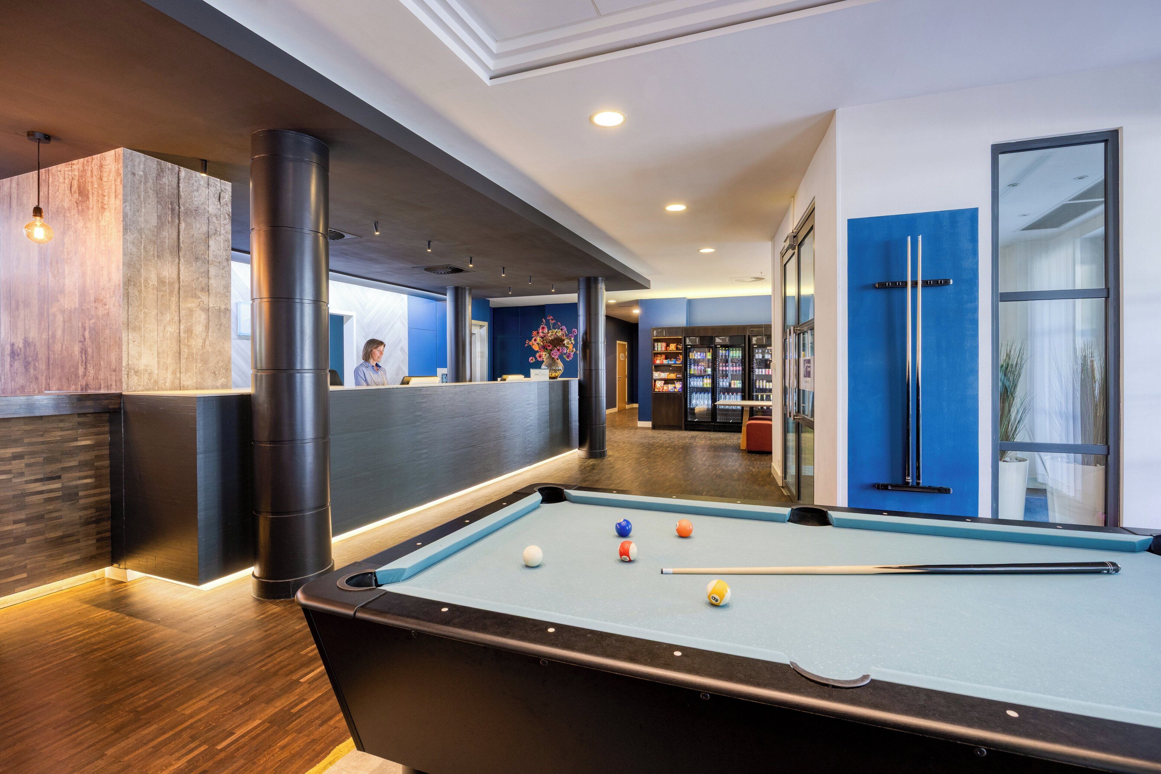 A pool table with balls, a reception desk, and a blue wall with a door.