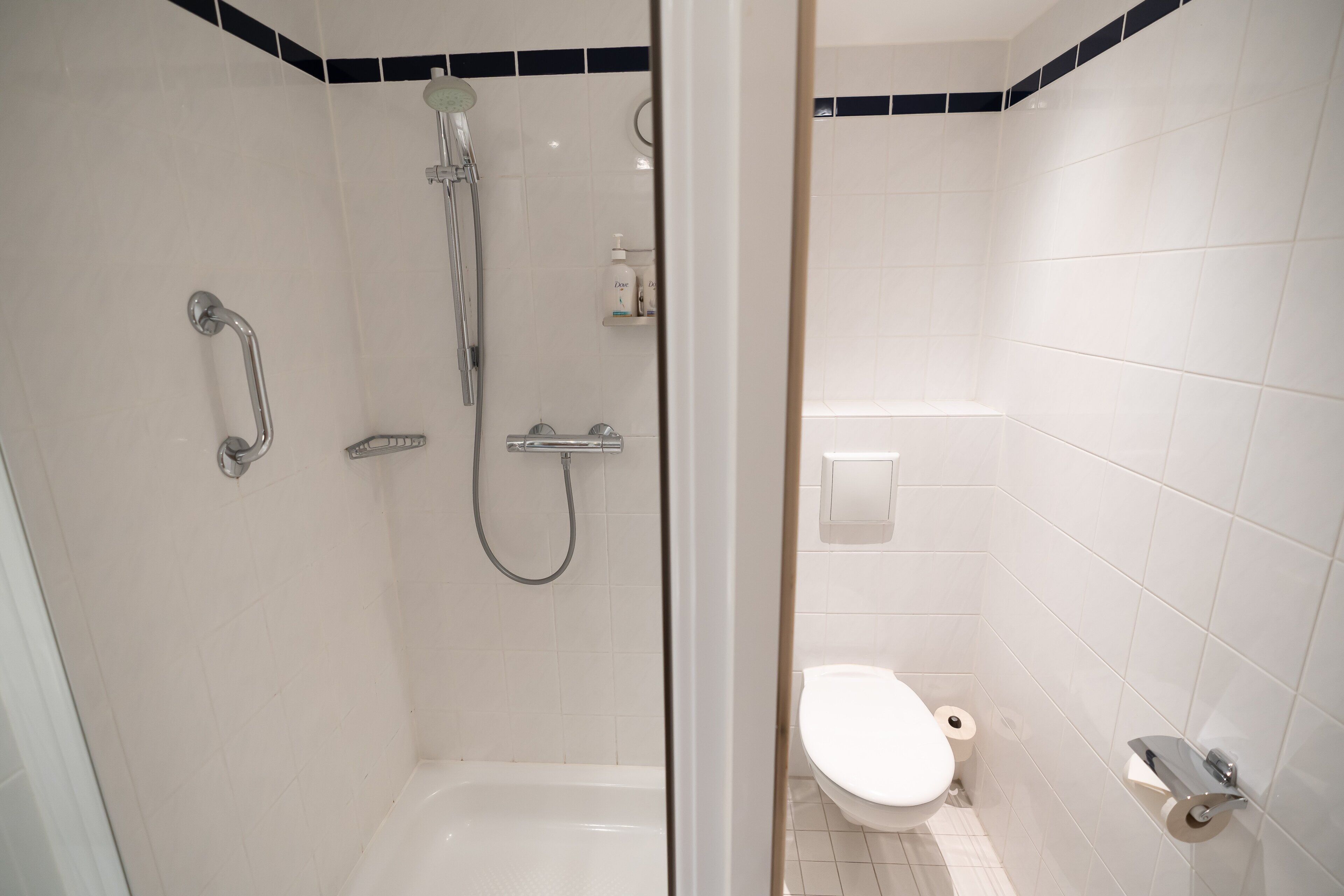 Een badkamer met een douche, toilet en handdroger.