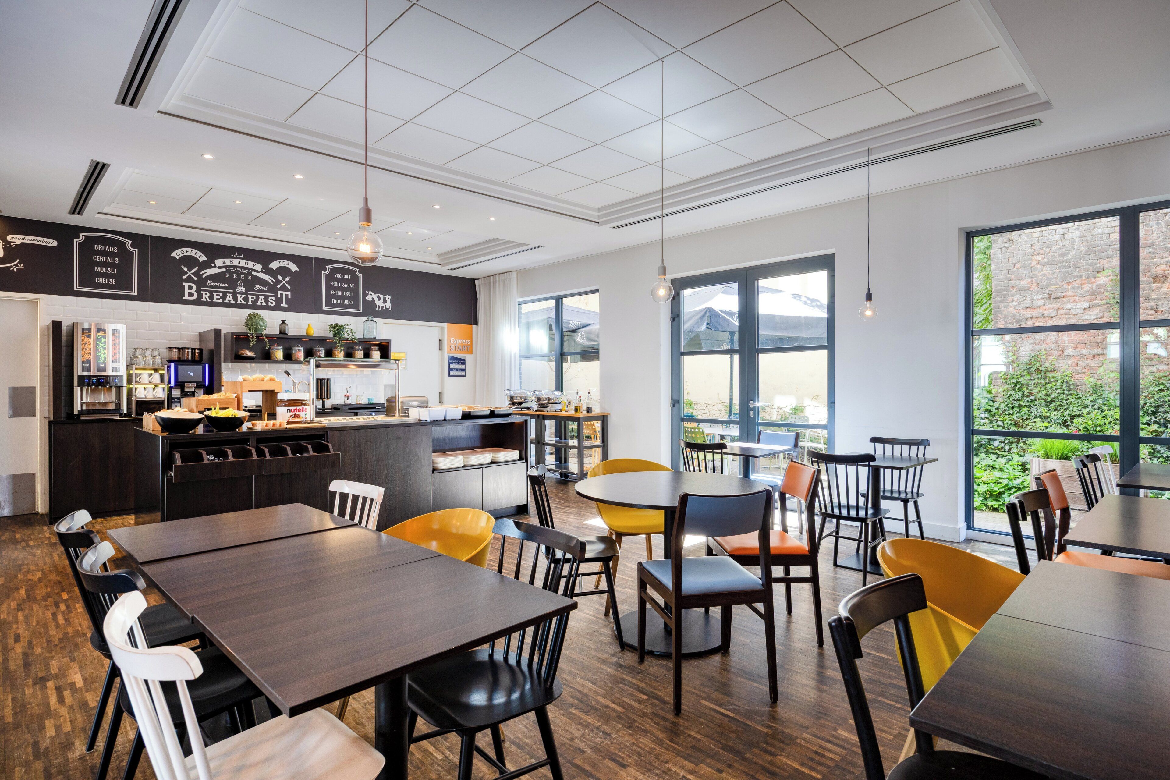 A modern cafe with a breakfast bar, seating area, and large windows.
