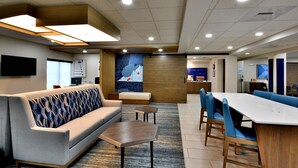 A modern hotel lobby with a sofa, a coffee table, and a long dining table with chairs. - Holiday Inn Express Richmond I-64 Short Pump Area by IHG (Richmond)