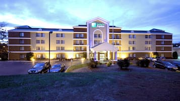 A Holiday Inn Express hotel with a central entrance, multiple parking spaces, and a well-lit facade.