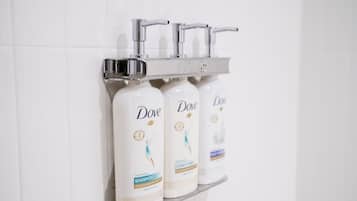 Three Dove shampoo bottles on a white tiled wall.