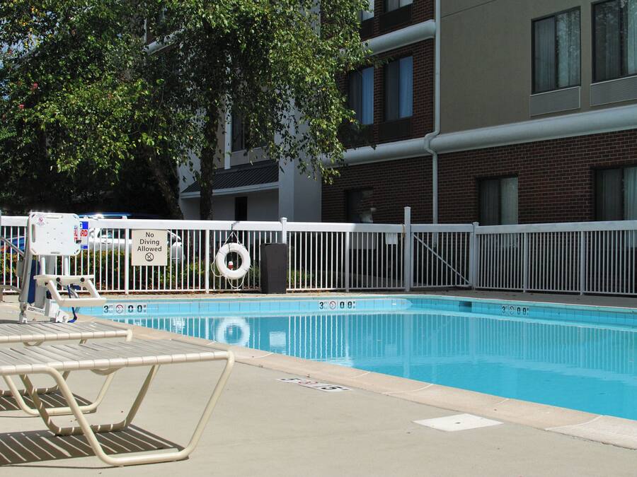 A swimming pool with a white fence, lounge chairs, and a lifebuoy.