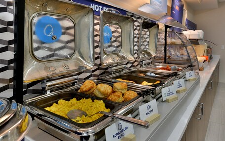 A buffet with labeled sections for scrambled eggs, biscuits, turkey sausage, and other items.