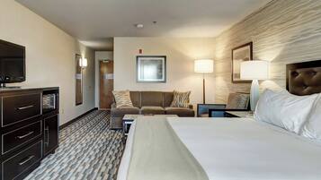 Una habitación de hotel con cama, televisor, escritorio, sofá y lámpara.
