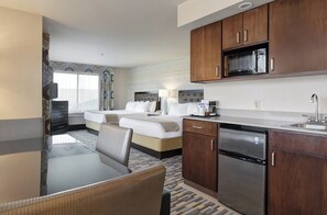 A hotel room with a dining table, two beds, a kitchen area with a microwave, and a dishwasher. - Holiday Inn Express Hotel & Suites Warwick-Providence (Arpt) by IHG (Warwick)