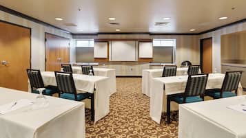 A conference room with multiple tables and chairs, a patterned carpet, and a neutral color scheme.