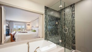 A modern bathroom with a glass-enclosed shower, a large mirror, and a bathtub.