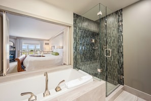 A modern bathroom with a glass-enclosed shower, a large mirror, and a bathtub.