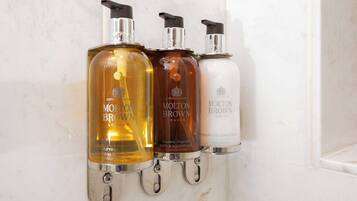 Drie flessen Molton Brown bad- en douchegel in verschillende kleuren.