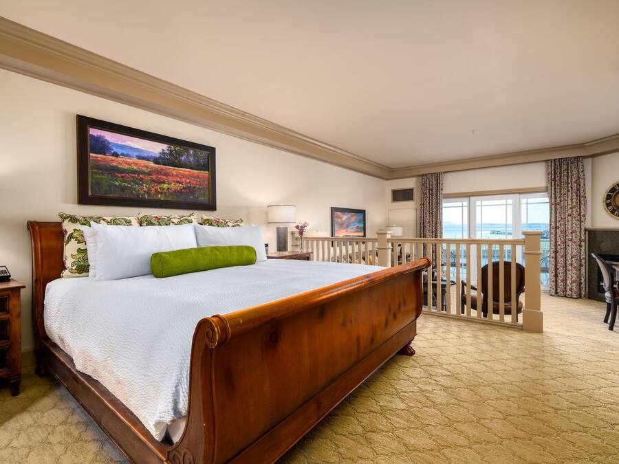 Un dormitorio espacioso con una cama grande, un balcón con barandilla y vistas al mar.