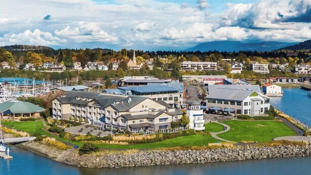 A coastal hotel with multiple buildings, a marina, and a view of the surrounding landscape.