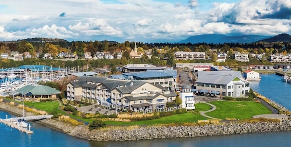 A coastal hotel with multiple buildings, a marina, and a view of the surrounding landscape.
