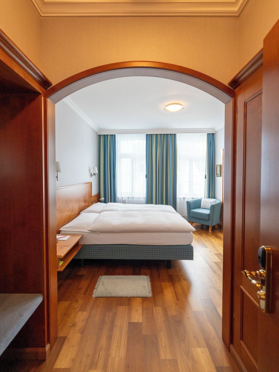 A hotel room with a bed, a desk, a chair, and a small sofa.