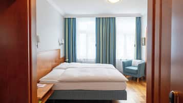 A hotel room with a bed, a desk, a chair, and a small sofa.