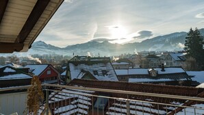A view from a balcony with a snow-covered town and mountains in the background.