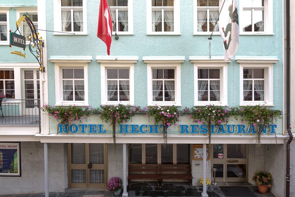 Hotel Hecht Restaurant features a charming exterior with a light blue facade, white window frames, and a prominent sign above the entrance.