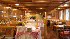 A dining area with tables set for breakfast, including fruits and beverages.