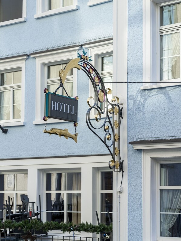 A hotel sign with a decorative metal frame and a hanging ornament.
