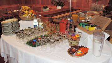 A buffet table with various food items, including a fruit basket, bottles, and a box of tea.