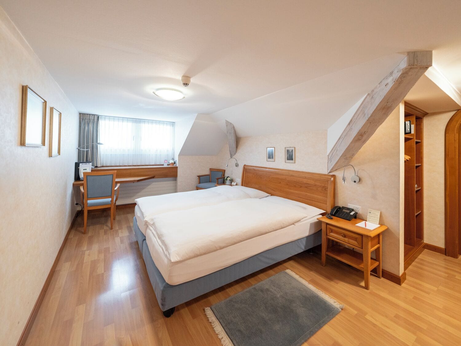 Una camera da letto con un letto grande, una scrivania e una sedia. Si vede una scala che conduce a un piano superiore.