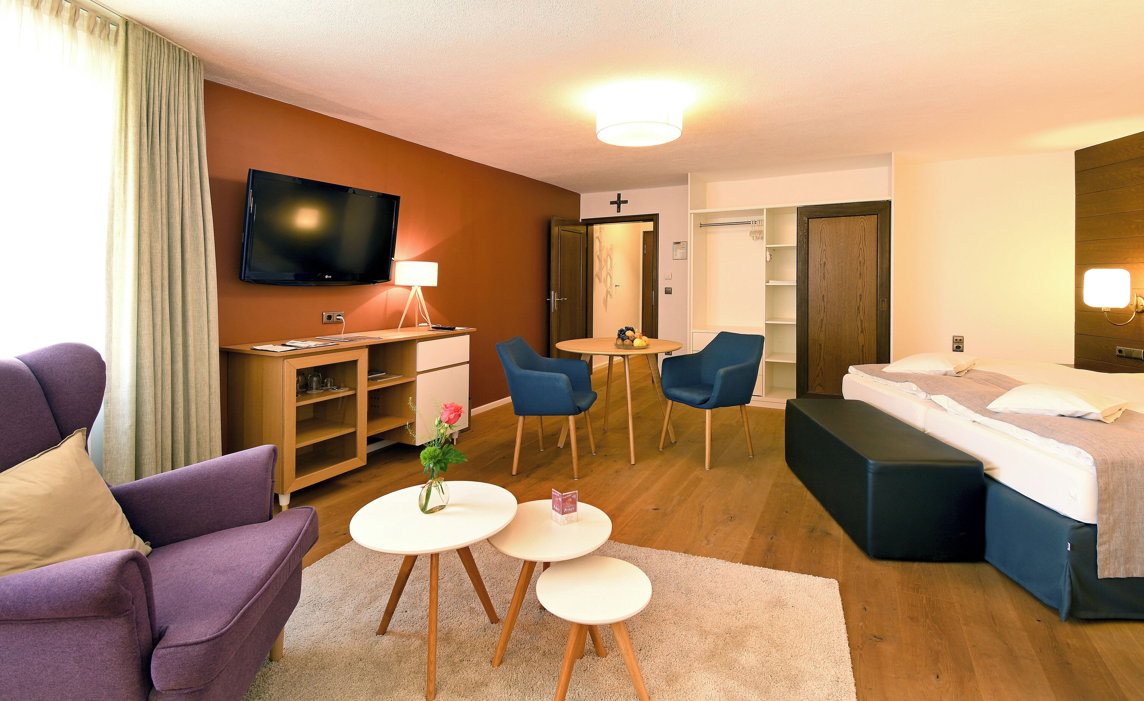 A hotel room with a TV, a desk, a bed, and two chairs.
