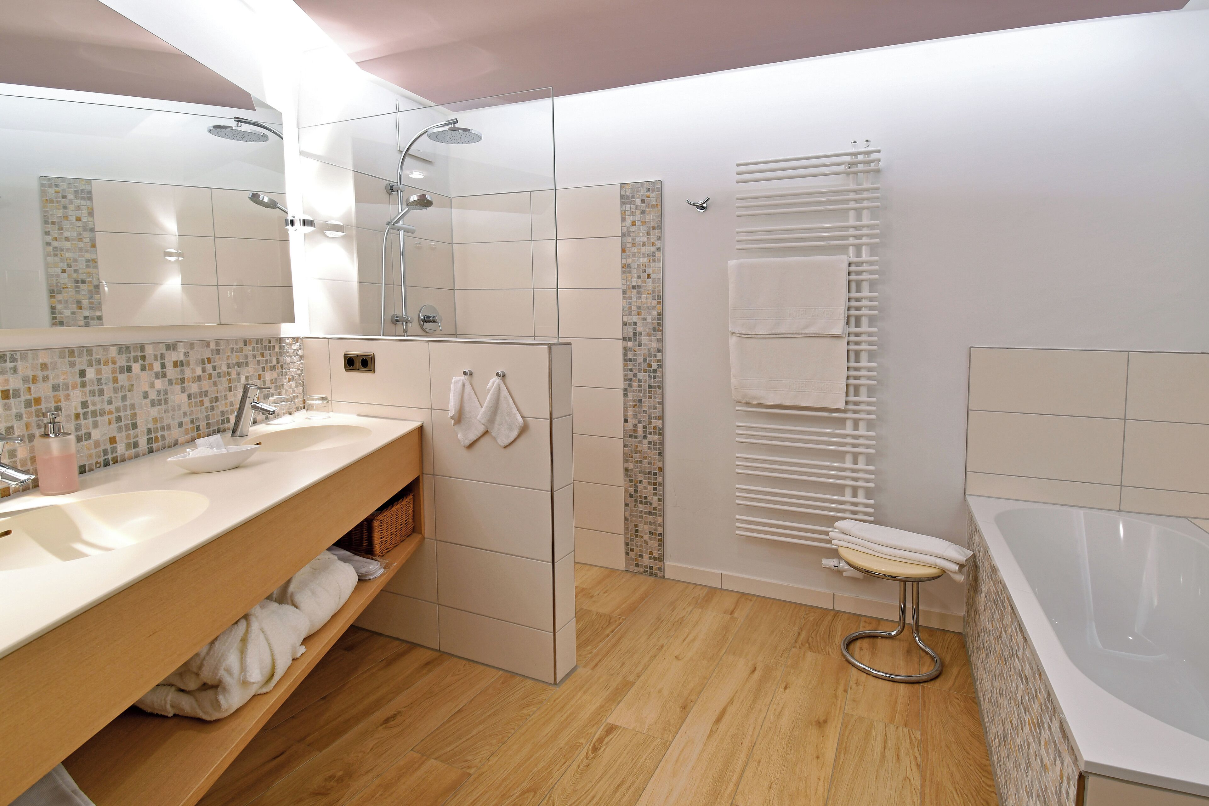 A modern bathroom with a large mirror, two sinks, a shower, and a bathtub.
