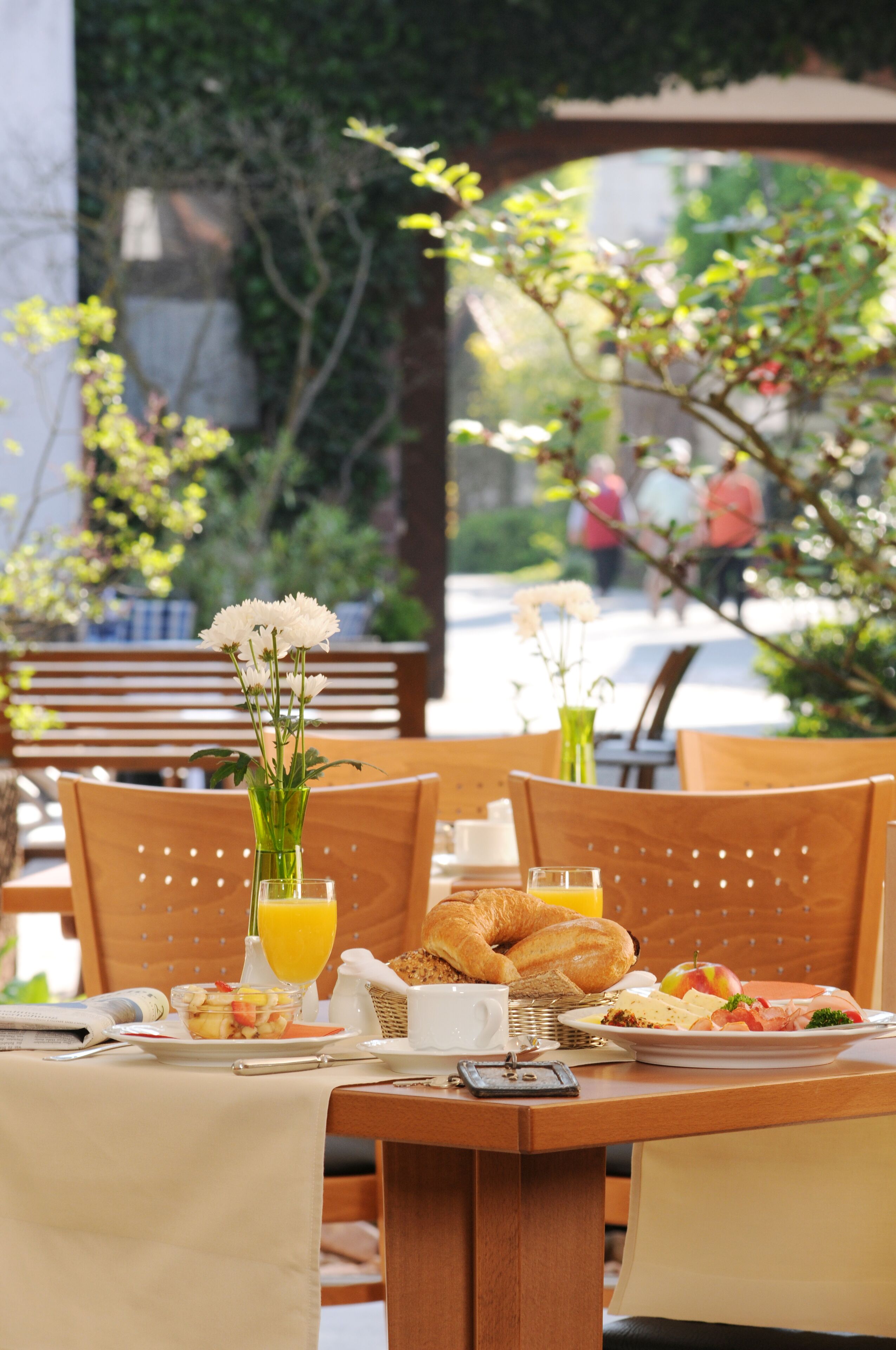 A breakfast table with croissants, fruit, and a vase of flowers.