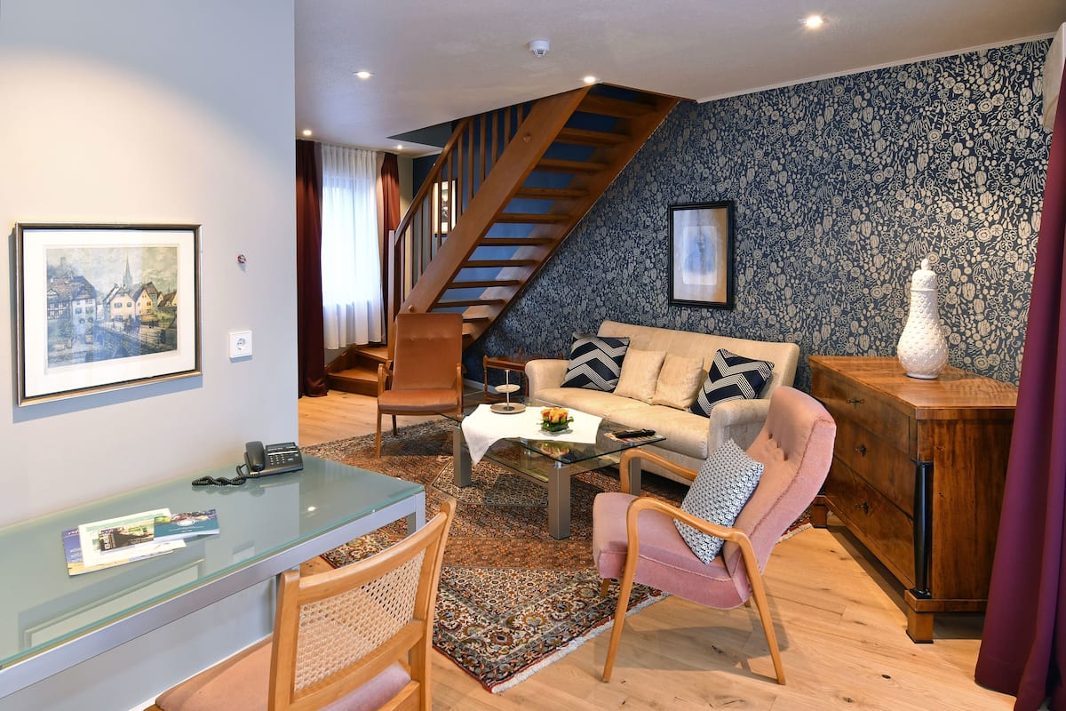 Uma sala de estar moderna com escada, sofá, mesa de centro e área de jantar com mesa de vidro.