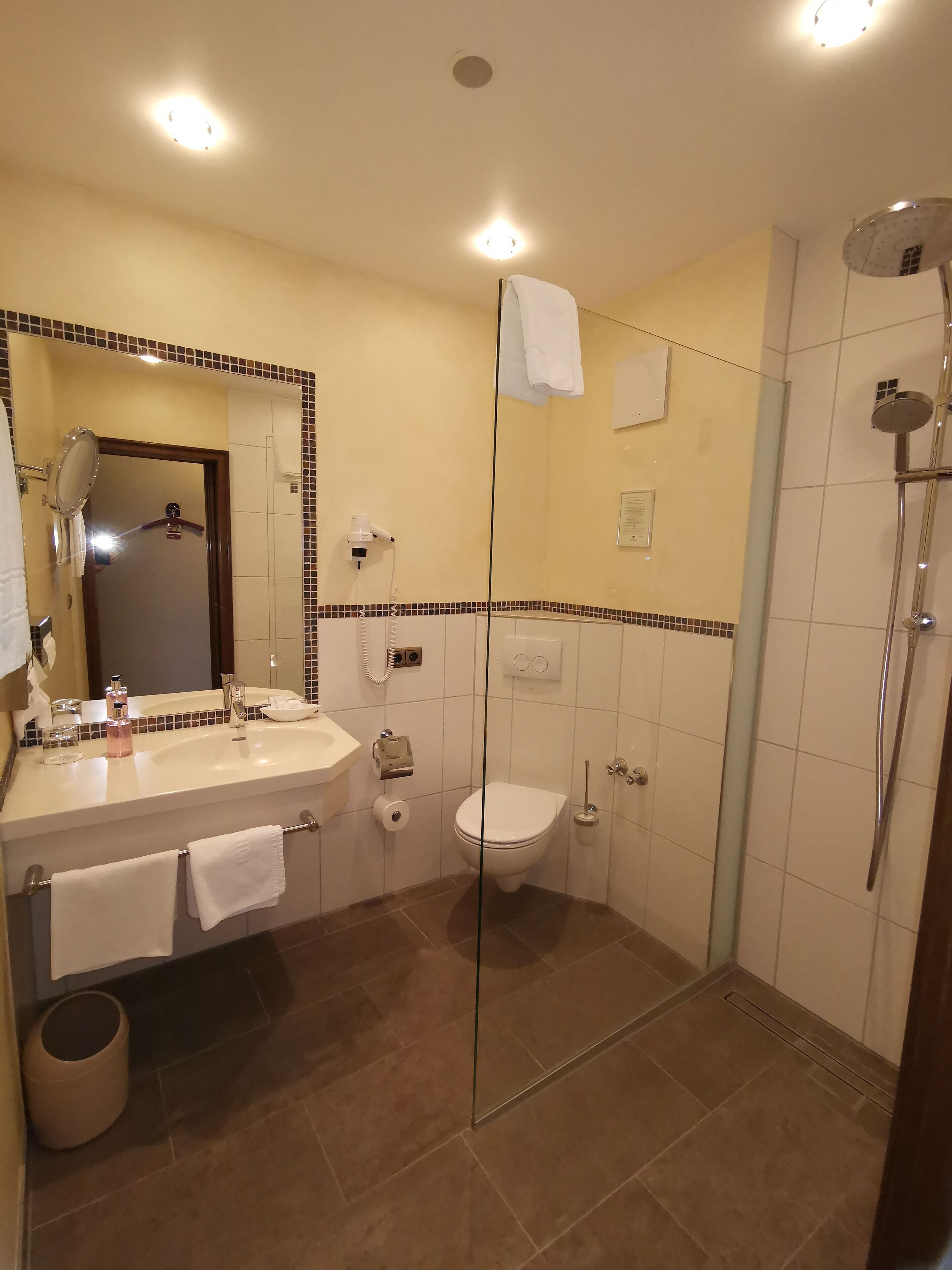Ein Badezimmer mit Waschbecken, Spiegel, Toilette und Dusche.