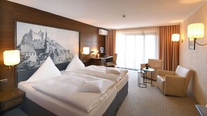 A hotel room with a large bed, a desk, two chairs, a small table, and a large wall mural. - Hotel Anker (Marktheidenfeld)