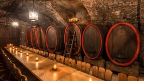 A long wooden table with candles, surrounded by wooden chairs, in a rustic cellar with wooden barrels and a ladder. - Hotel Anker (Marktheidenfeld)