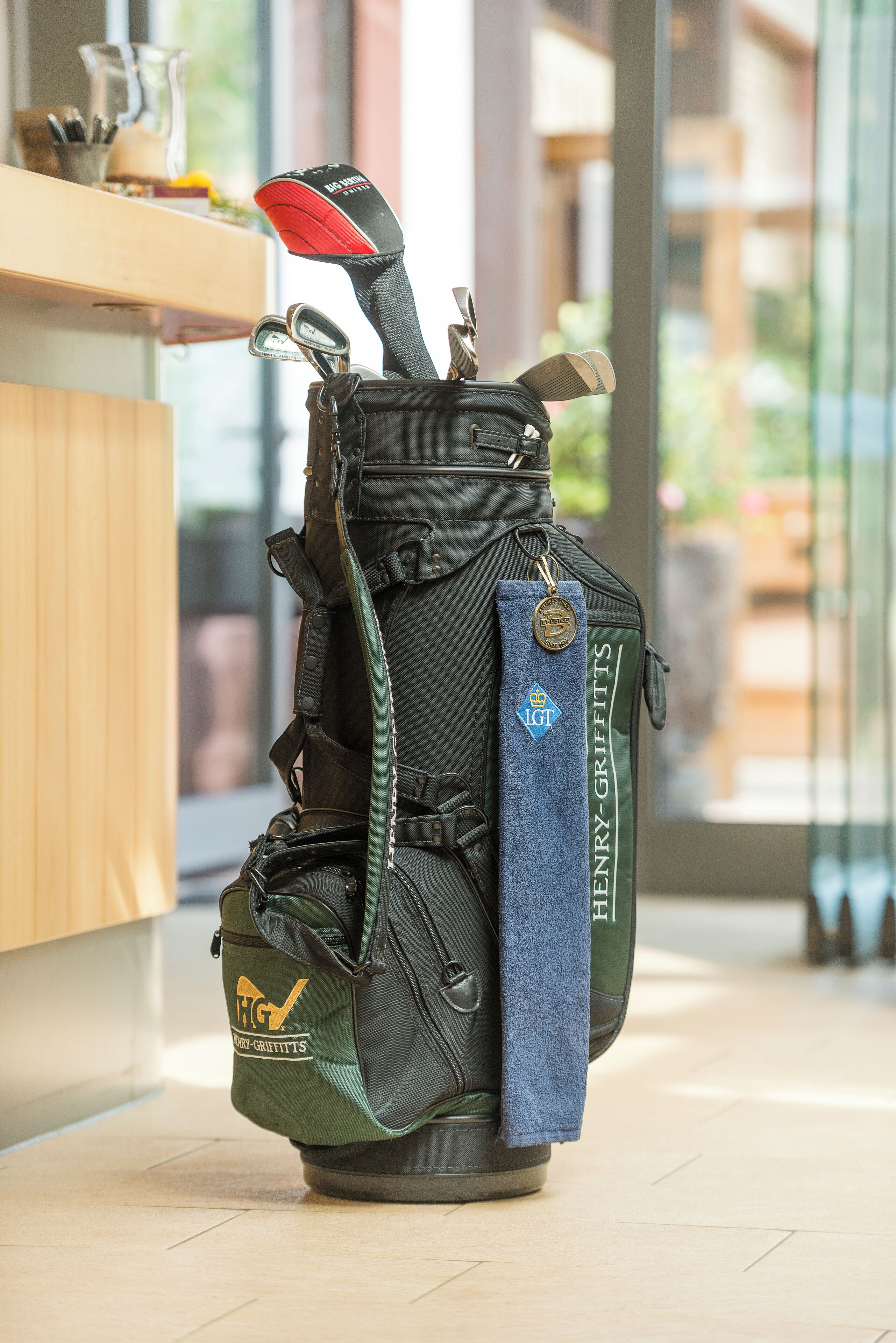 Eine Golftasche mit Handtuch und Golfschläger auf Holzboden.