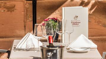A table set for dining with a menu, wine glasses, a bottle of wine, and a vase of flowers.