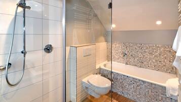 Un baño moderno con ducha envuelta en vidrio, inodoro y bañera.