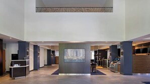 A spacious lobby with a reception desk, a large abstract artwork, and a Starbucks coffee machine.