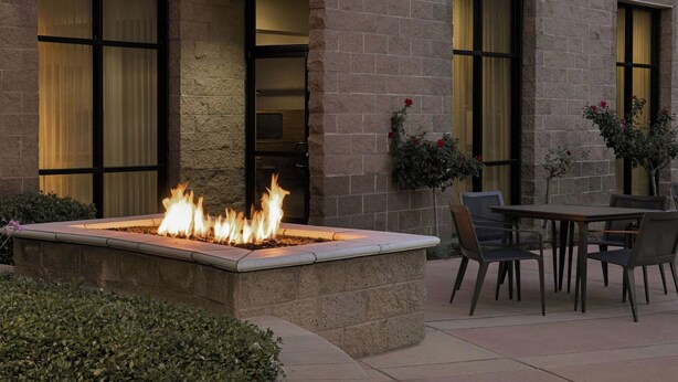 A stone building with large windows, a fire feature, and outdoor seating.