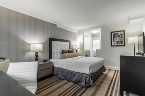 Una habitación de hotel con una cama grande, un escritorio, una silla, un aparador y un espejo.