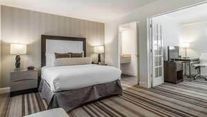 Ein Hotelzimmer mit einem großen Bett, zwei Nachttischen mit Lampen, einem Schreibtisch mit Stuhl und einem Kleiderschrank.