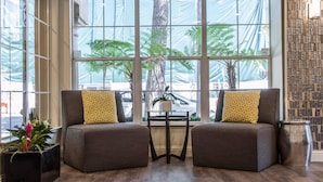 Ein Zimmer mit zwei grauen Sesseln, einem kleinen Tisch und einer Topfpflanze.