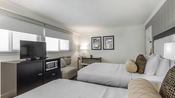 Une chambre d’hôtel avec deux lits, un bureau avec un ordinateur, un four à micro-ondes et une télévision.