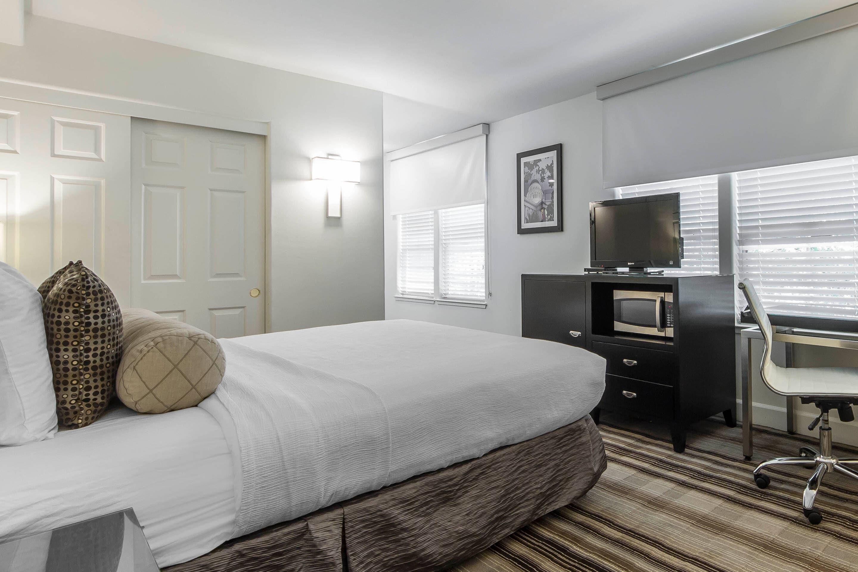 Ein Hotelzimmer mit Bett, Schreibtisch mit Computer, Fernseher und Mikrowelle.