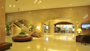 A spacious lobby with a curved staircase, a reception desk, and a seating area with a potted plant. - New Otani Inn Sapporo (Sapporo)