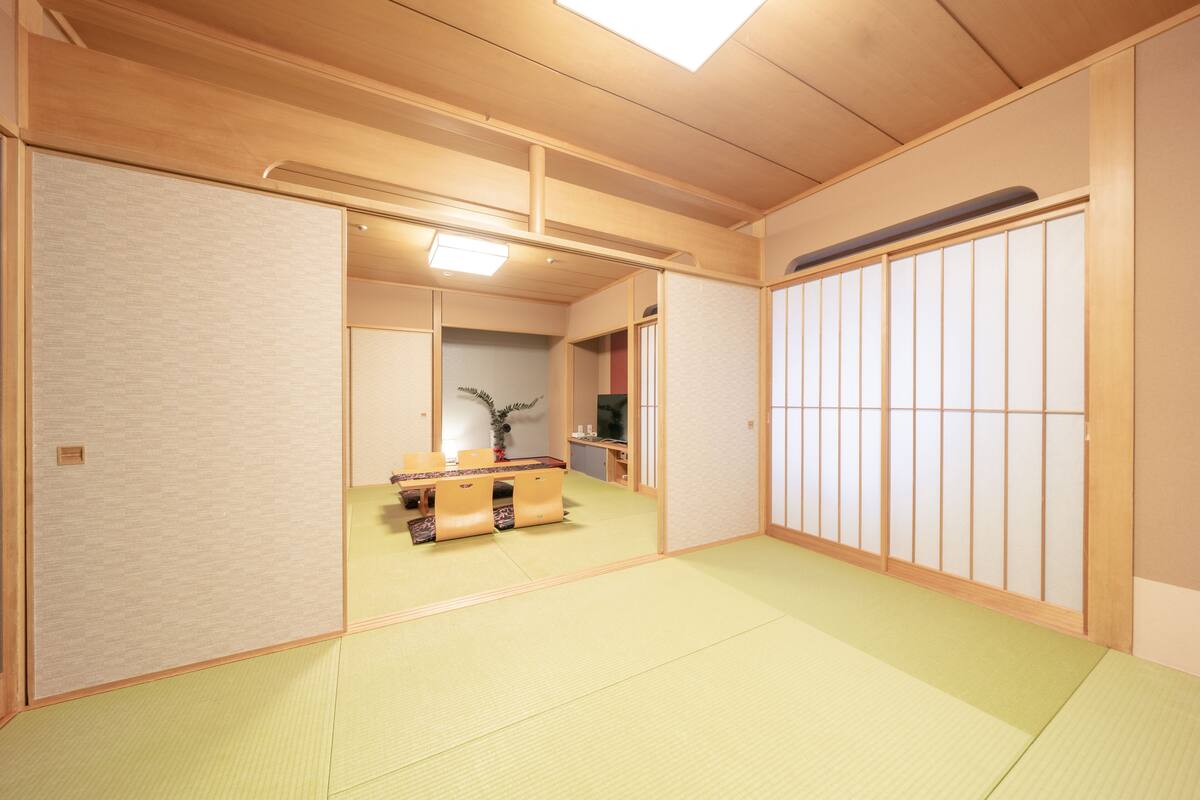 A traditional Japanese room with tatami flooring, sliding doors, and a low table with cushions.