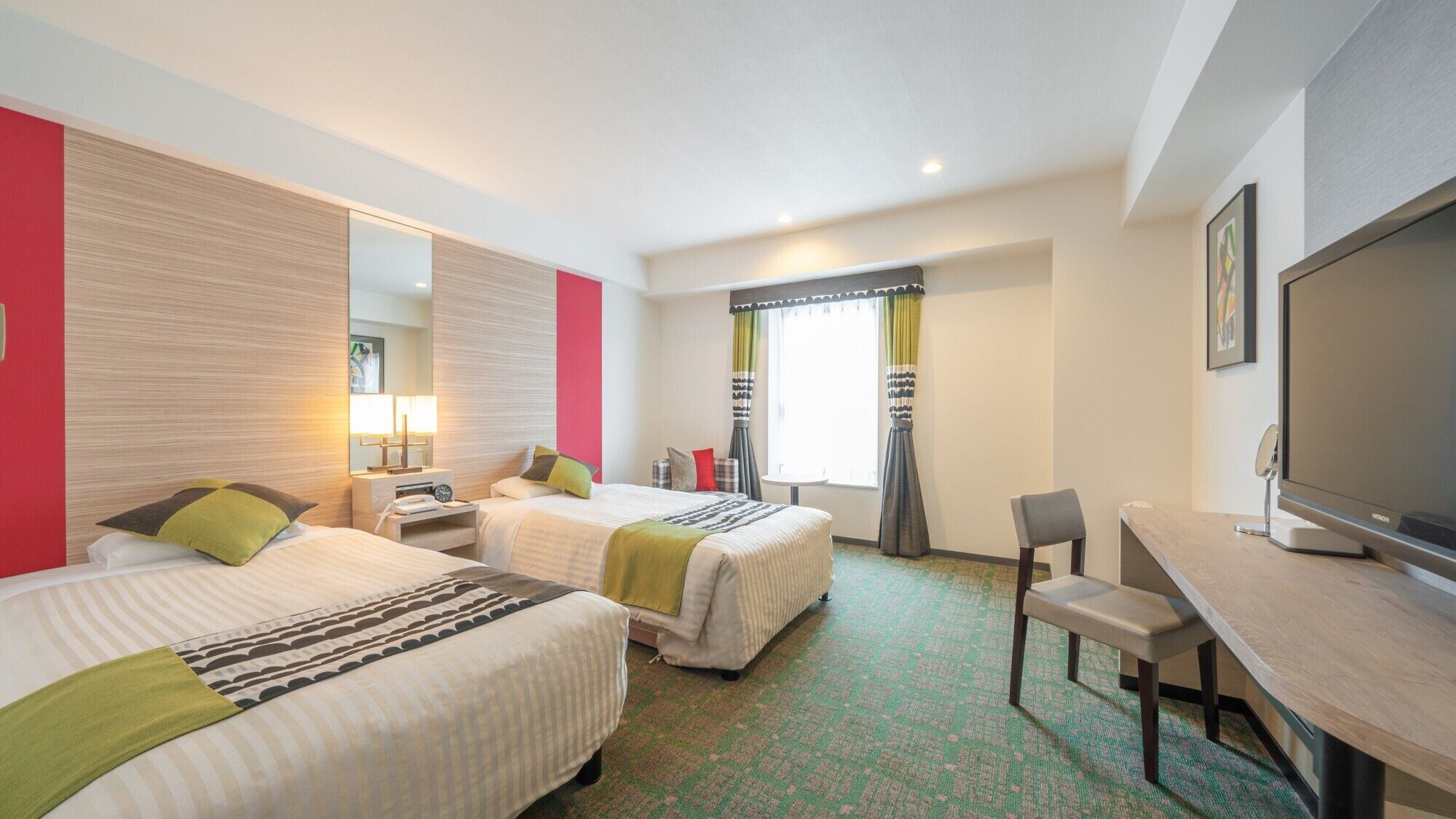 A hotel room with two beds, a desk, a chair, a television, and a window with curtains.