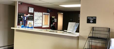 A reception desk with a bulletin board displaying various notices and a sign indicating a free smoking lounge.
