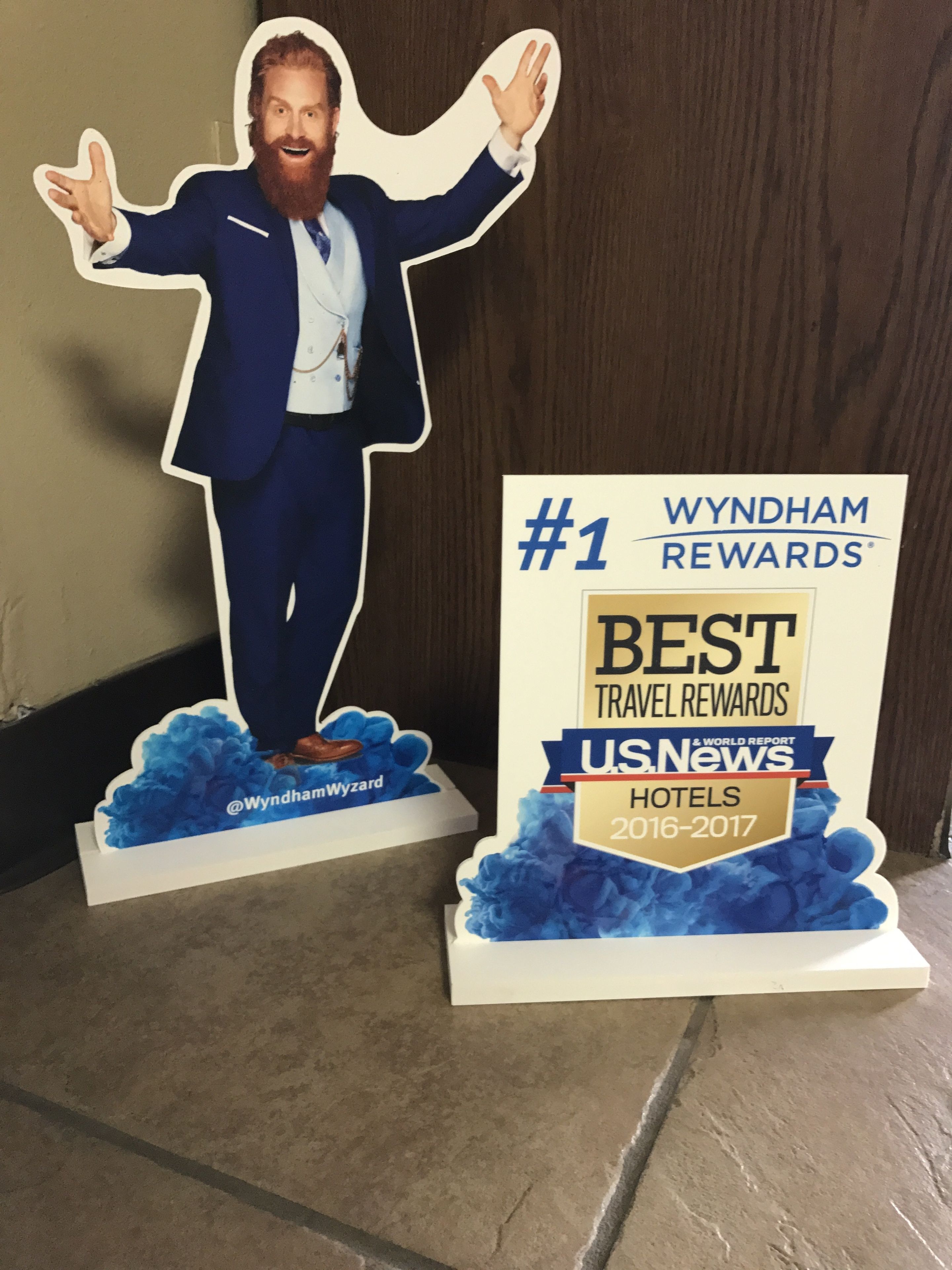Une silhouette découpée d’un homme en costume, sur un fond bleu, avec une pancarte indiquant : « WYNDHAM REWARDS, le meilleur programme de fidélité pour les voyages, selon U.S. News & World Report, hôtels, 2016-2017 ».